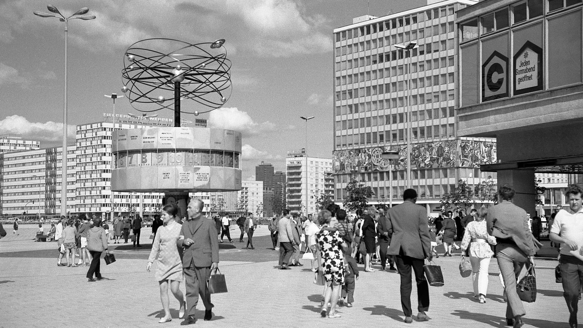 Historische Schwarzweiß-Aufnahme vom Alexanderplatz mit der Weltzeituhr kurz nach der Aufstellung 1969. Die Uhrenanlage mit einer symbolischen Weltdarstellung im Berliner Ortsteil Mitte enthält auf ihrer metallenen Rotunde die Namen von 148 Städten. 