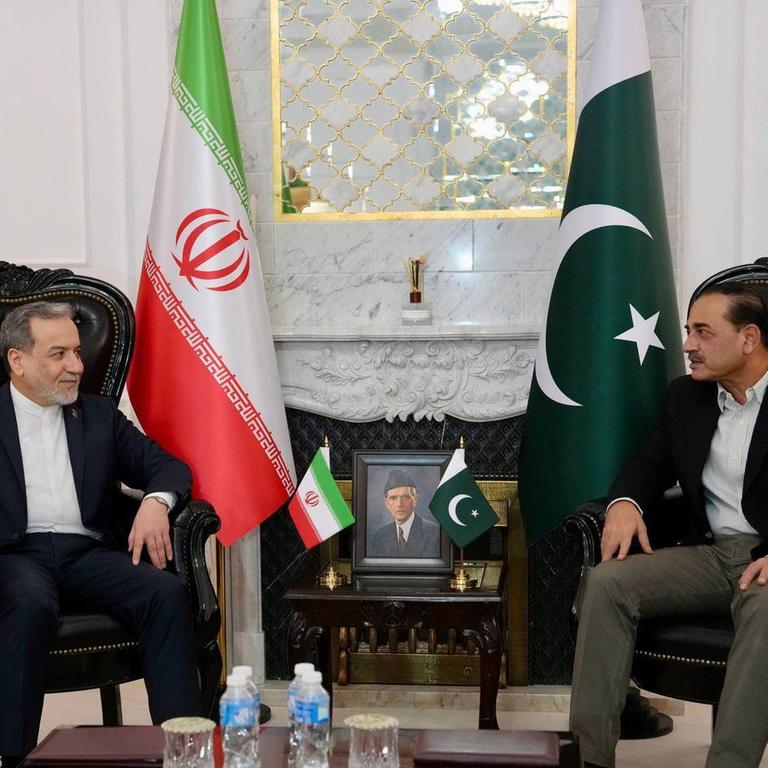 Irans Außenminister Araghtschi (l.) im Gespräch mit Pakistans Armeechef Munir. Beide sitzen auf Sesseln, im Hintergrund die Flaggen ihrer Länder.