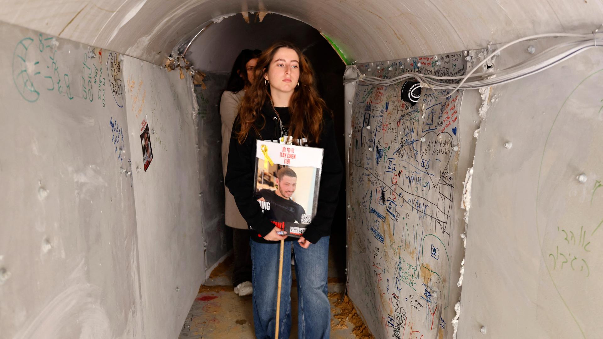 Angehörige tragen das Bild einer Hamas-Geisel durch den nachgebauten Tunnel.