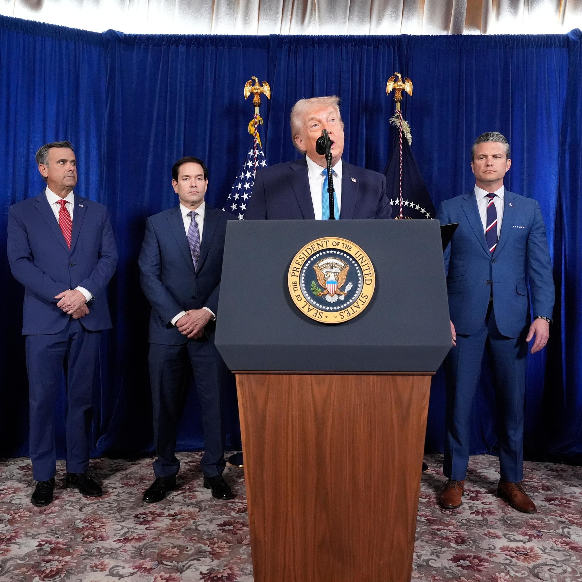 US-Präsident Donald Trump spricht an einem Rednerpult, dahinter Minister, Berater und ein General.