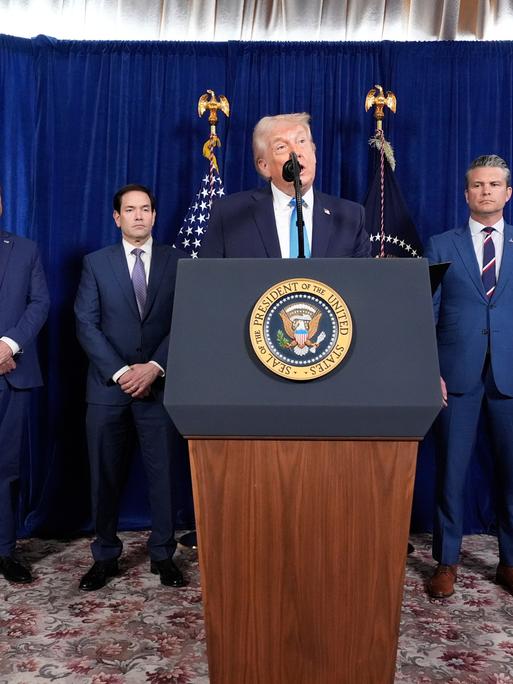 US-Präsident Donald Trump spricht an einem Rednerpult, dahinter Minister, Berater und ein General.