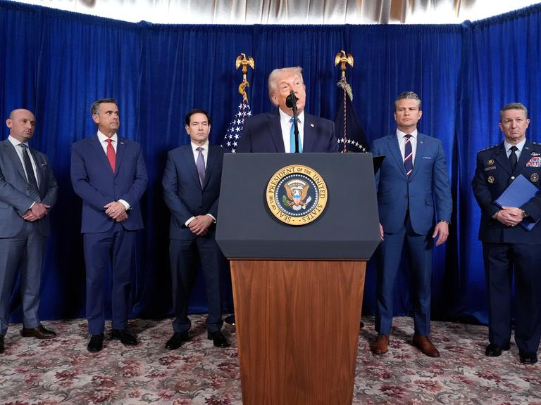 US-Präsident Donald Trump spricht an einem Rednerpult, dahinter Minister, Berater und ein General.