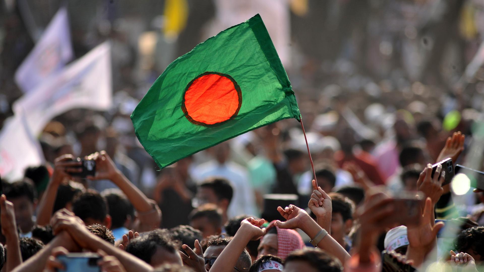 Das Bild zeigt eine Straßenszene aus dem Wahlkampf in Bangladesch. Zu sehen ist die Nationalflagge des Landes. 