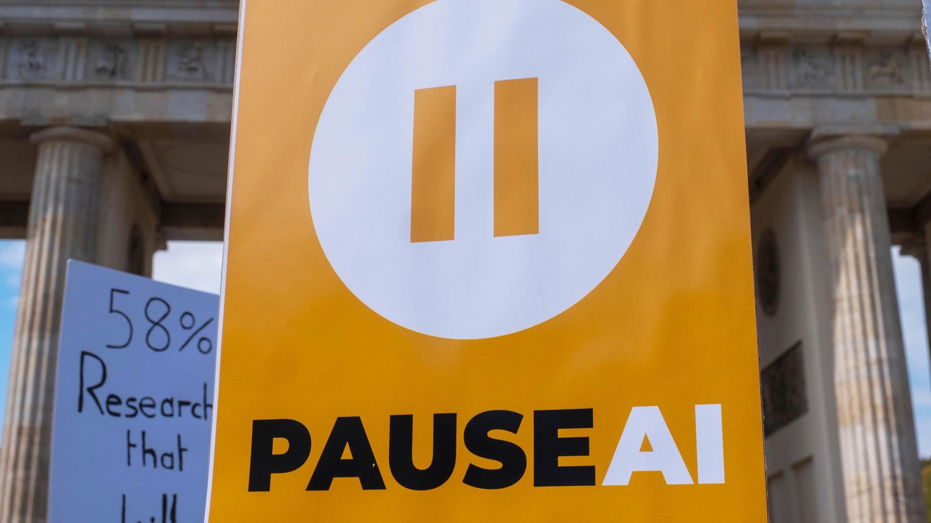 "PAUSE AI" steht auf einem Schild von Demonstranten am Brandenburger Tor