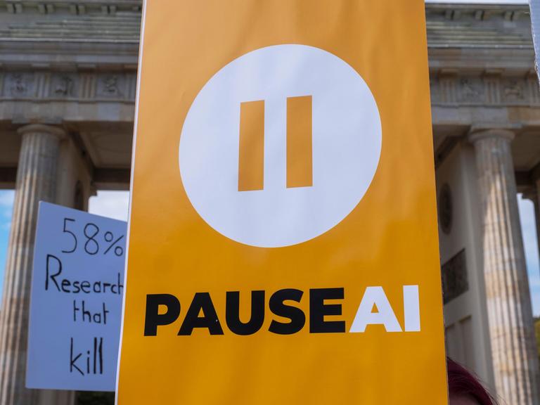 "PAUSE AI" steht auf einem Schild von Demonstranten am Brandenburger Tor "PAUSE AI" steht auf einem Schild von Demonstranten am Brandenburger Tor
