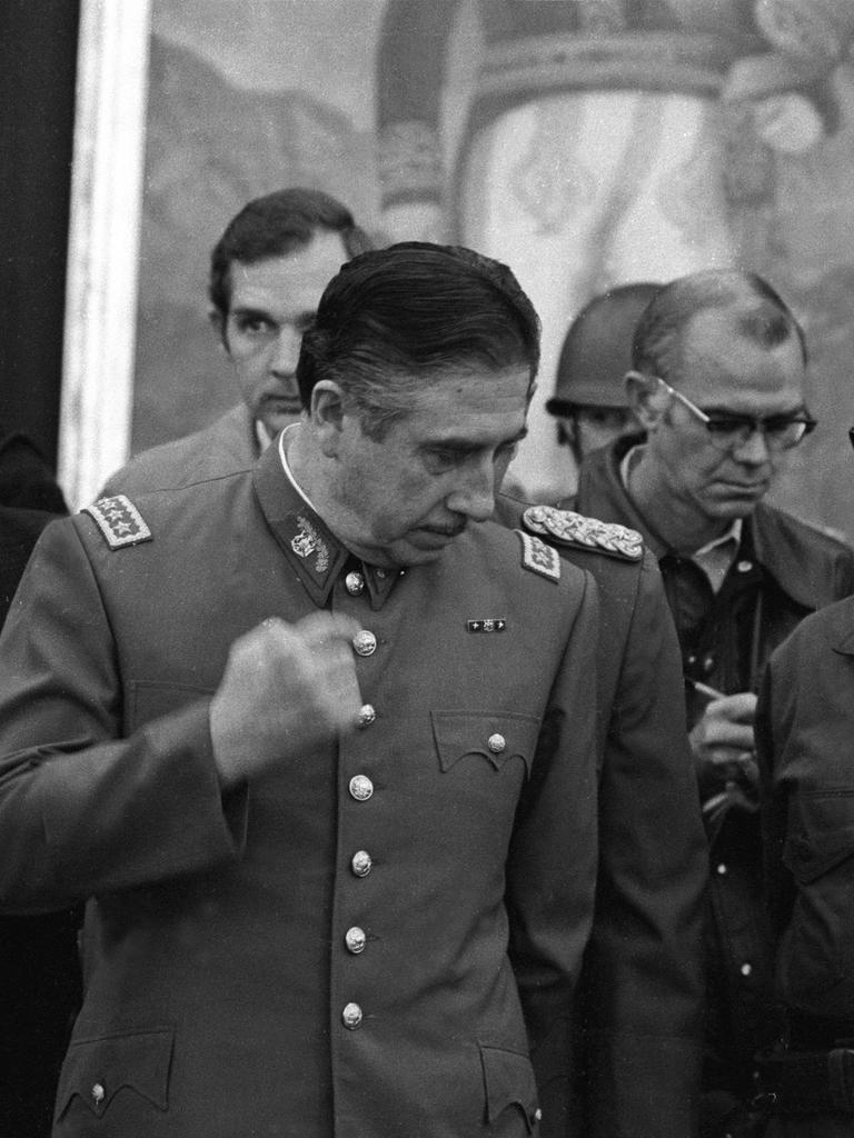 Augusto Pinochet umringt von Getreuen im Sepember 1973 bei seiner ersten Pressekonferenz nach dem Putsch gegen Salvador Allende in Chile. Er trägt Uniform und bewegt die rechte Faust von oben nach unten.
