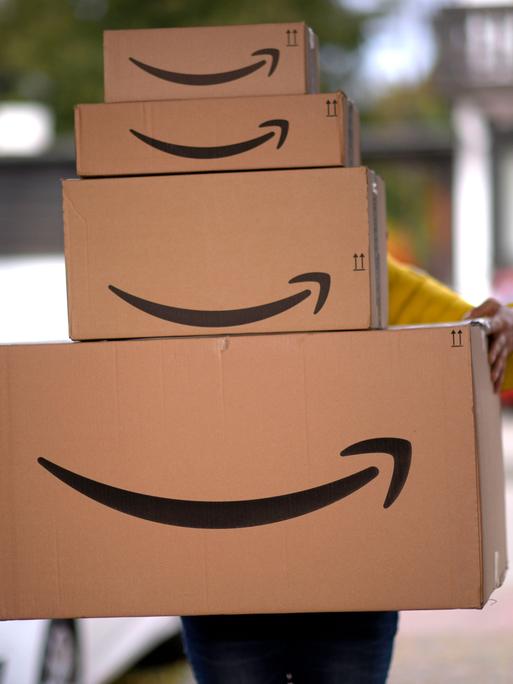 Ein Lieferbote liefert mehrere Pakete von Amazon an einer Haustür ab.