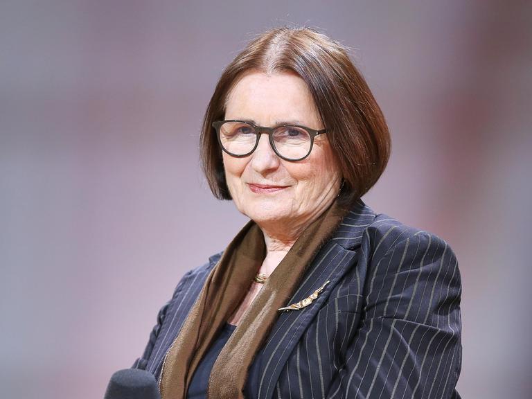 Die russische Publizistin Irina Scherbakowa im Porträt. Sie trägt einen gestreifte blaugrauen Blazer mit braunem Schal, eine Brille und hat braune kurze Haare. 