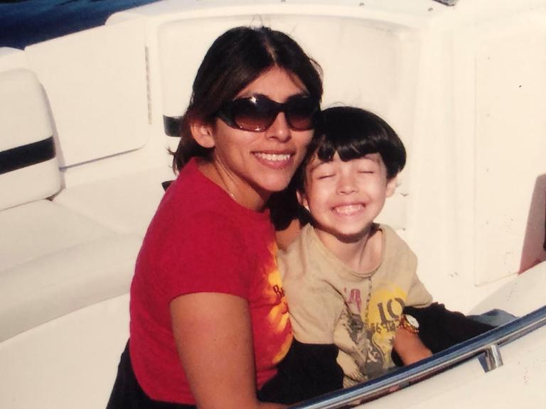 Mutter Gina mit Sonnenbrille und Sohn Aidan auf einem Boot.