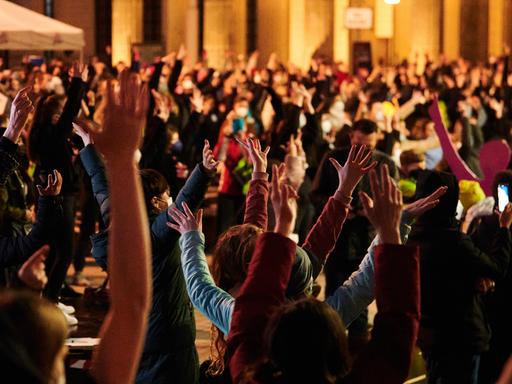 Teilnehmerinnen und Teilnehmer der Aktion One Billion Rising strecken die Hände in die höhe. One Billion Rising ist eine weltweite Bewegung, die am Valentinstag überall auf der Welt an öffentlichen Plätzen tanzend demonstriert, um ein Ende der Gewalt an Mädchen und Frauen einzufordern.