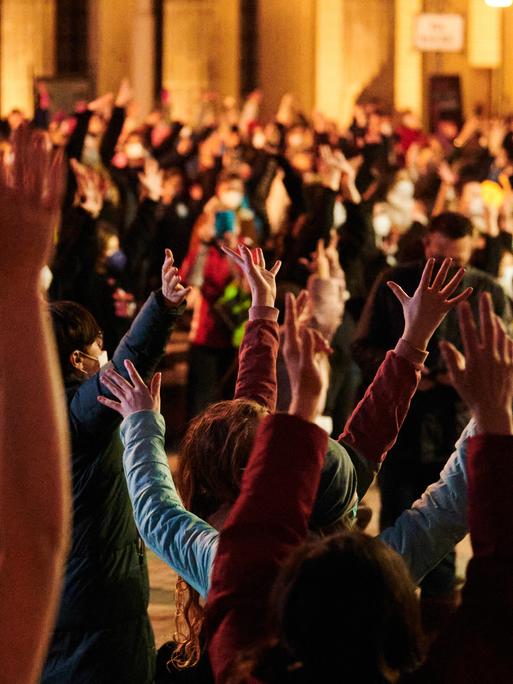 Teilnehmerinnen und Teilnehmer der Aktion One Billion Rising strecken die Hände in die höhe. One Billion Rising ist eine weltweite Bewegung, die am Valentinstag überall auf der Welt an öffentlichen Plätzen tanzend demonstriert, um ein Ende der Gewalt an Mädchen und Frauen einzufordern.