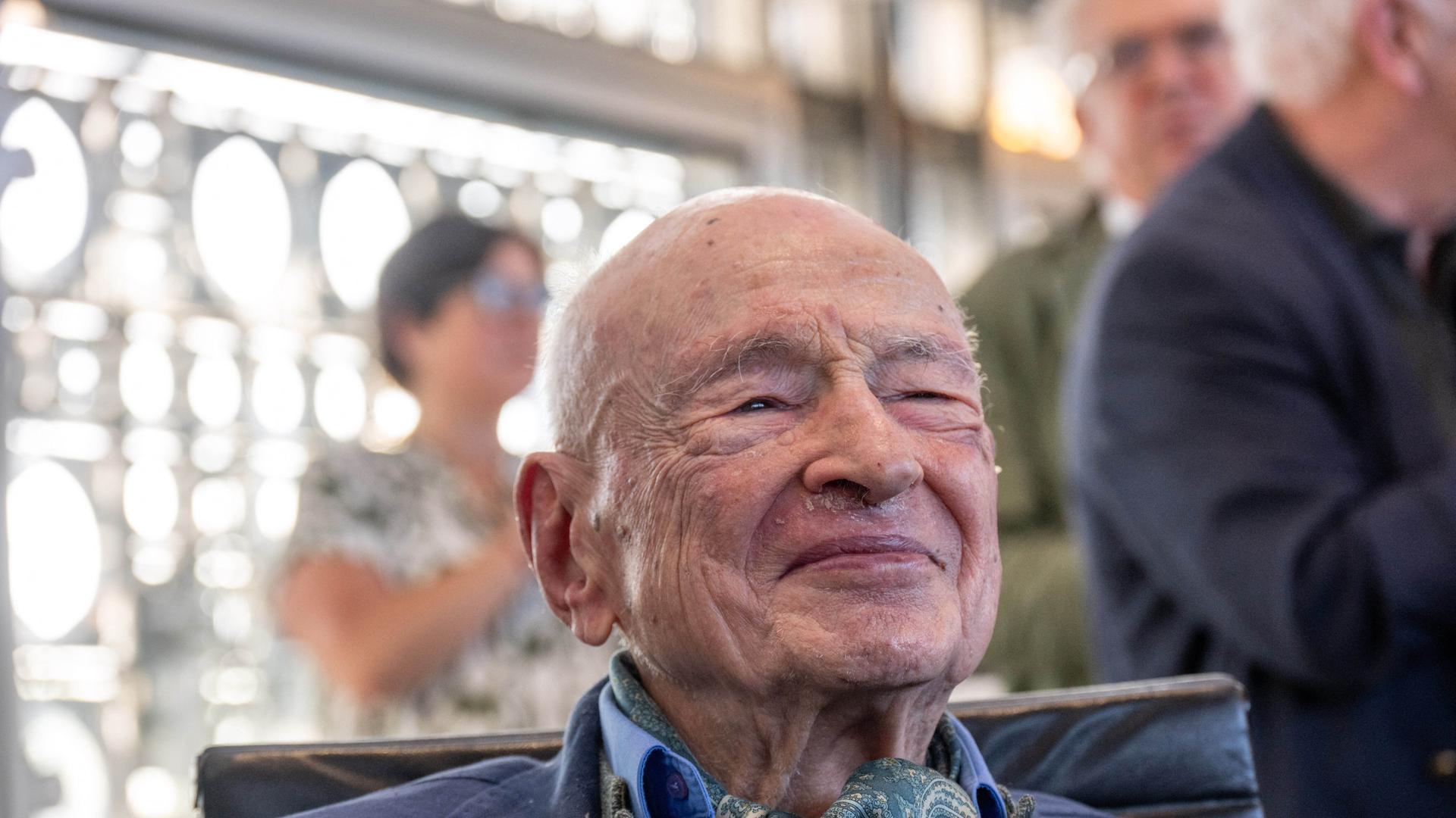 Das Foto zeigt den Kopf des lächelnden Philosophen und Soziologen Edgar Morin in einem Raum. Dahinter vor einem Fenster weitere Personen. Das Foto zeigt den Kopf des lächelnden Philosophen und Soziologen Edgar Morin in einem Raum. Dahinter vor einem Fenster weitere Personen.