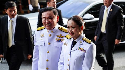 Paetongtarn Shinawatra mit ihrem Vater Thaksin Shinawatra. Beide tragen weisse Uniformen.
