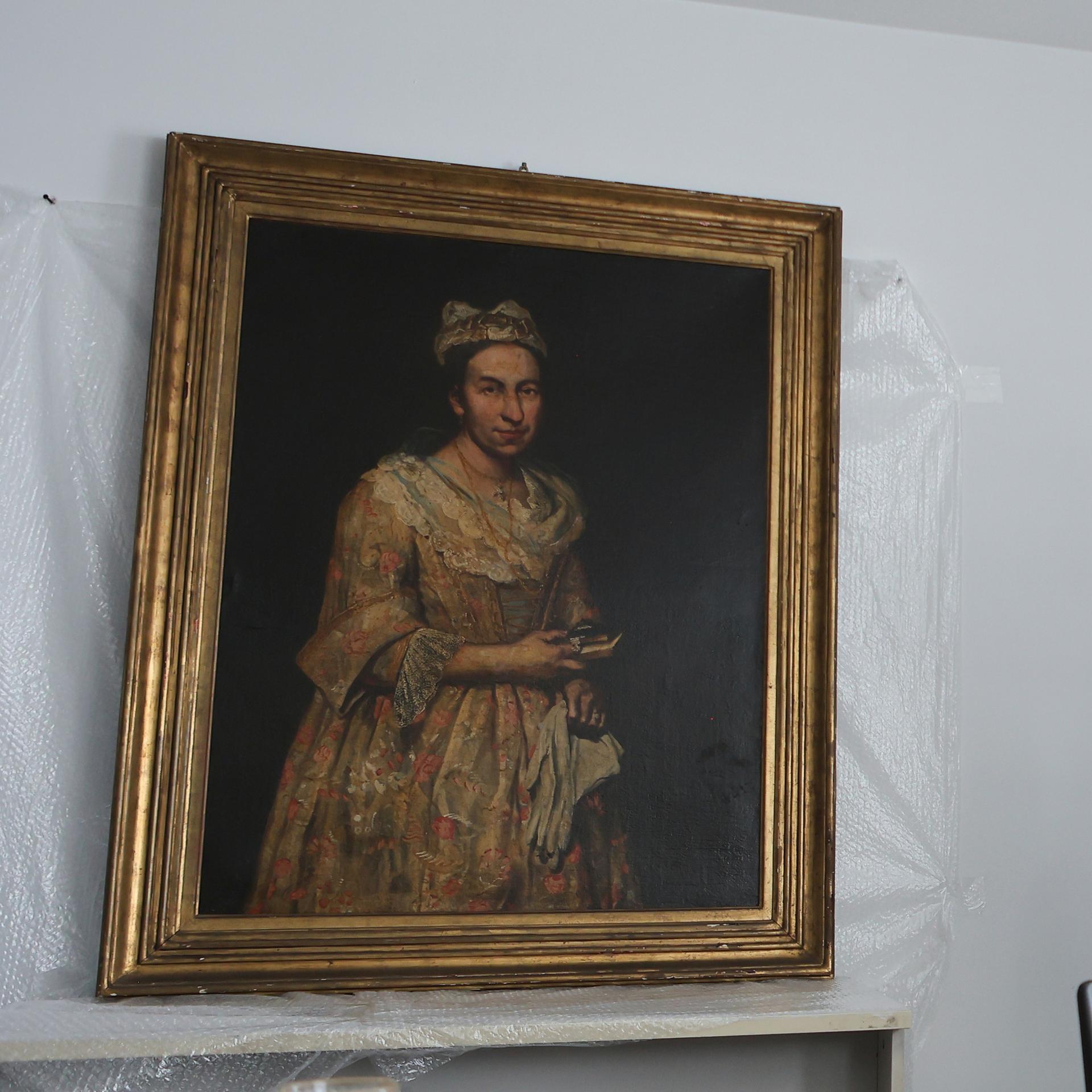 Giacomo Cerutis Gemälde "Porträt einer Dame" aus dem 18. Jahrhundert hängt an einer weißen Wand. Zwischen Bild und Wand ist Plastikfolie. Neben dem Bild steht ein Mann mit Bart. 