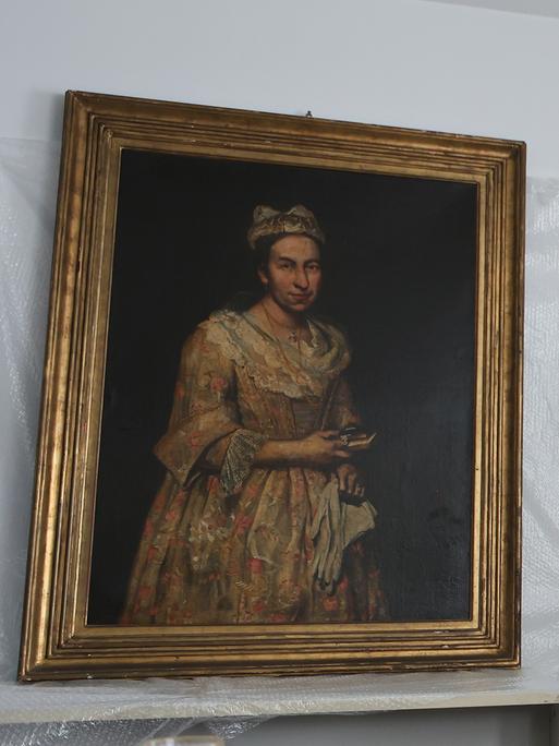 Giacomo Cerutis Gemälde "Porträt einer Dame" aus dem 18. Jahrhundert hängt an einer weißen Wand. Zwischen Bild und Wand ist Plastikfolie. Neben dem Bild steht ein Mann mit Bart. Giacomo Cerutis Gemälde "Porträt einer Dame" aus dem 18. Jahrhundert hängt an einer weißen Wand. Zwischen Bild und Wand ist Plastikfolie. Neben dem Bild steht ein Mann mit Bart.