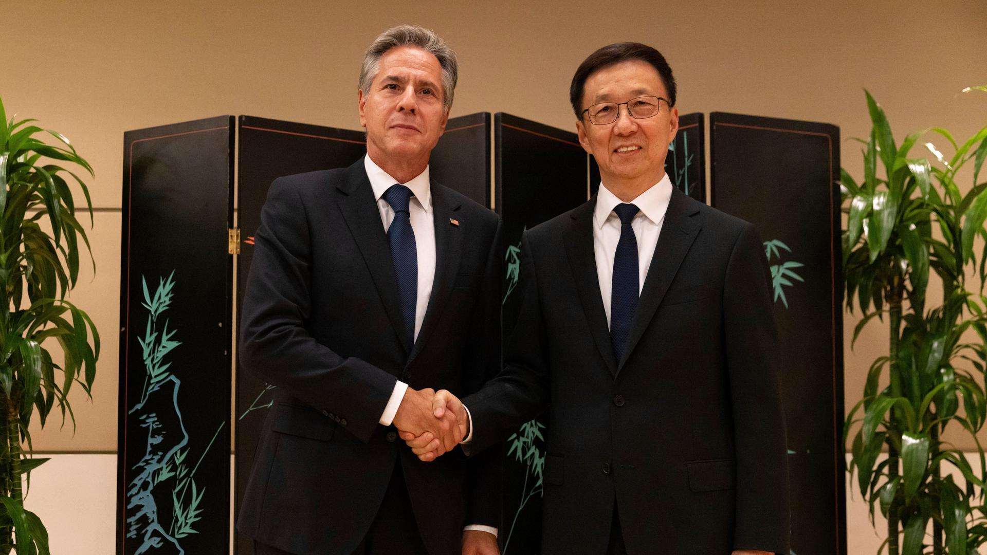 US-Außenminister Anthony Blinken und chinesische Vizepräsident Han Zheng schütteln sich die Hände und blicken in die Kamera.