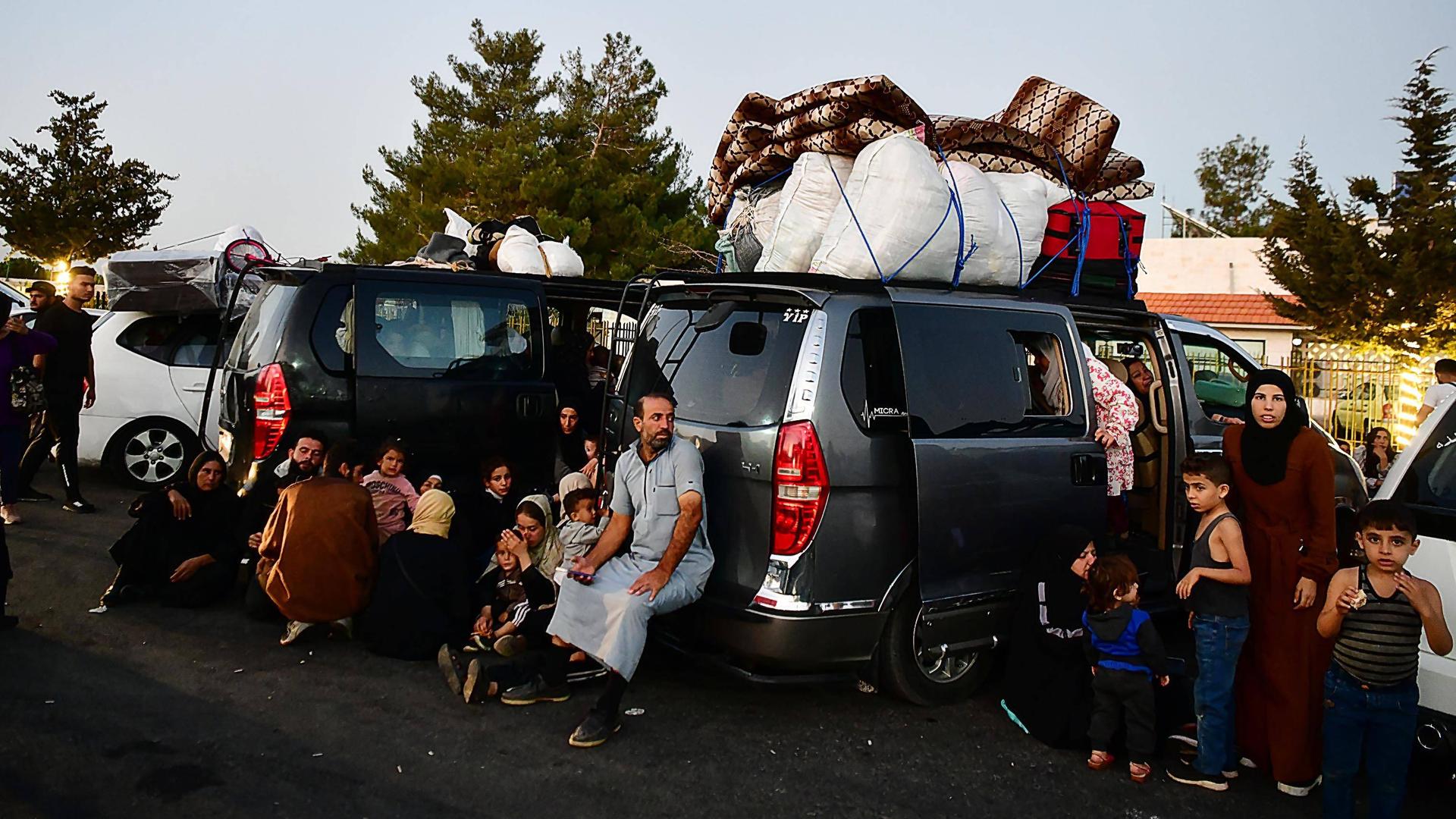 Das Foto zeigt voll bepackte Autos und Erwachsene und Kinder.