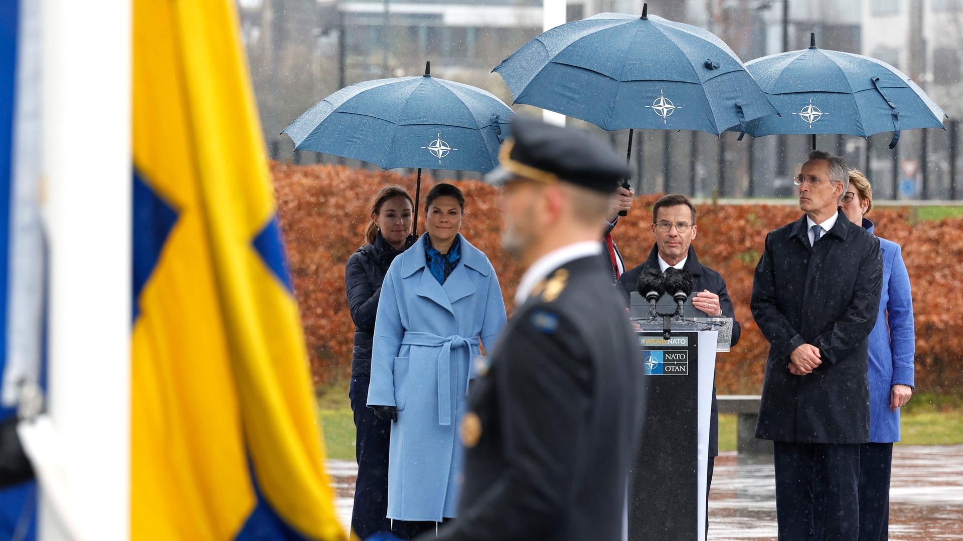 Schwedens Kronprinzessin Victoria (l-r), Ulf Kristersson, Ministerpräsident von Schweden, und Jens Stoltenberg, NATO-Generalsekretär, verfolgen vor dem NATO-Hauptquartier die Zeremonie zur Aufnahme Schwedens.