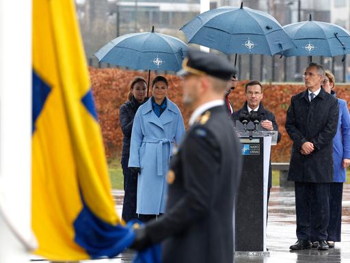 Schwedens Kronprinzessin Victoria (l-r), Ulf Kristersson, Ministerpräsident von Schweden, und Jens Stoltenberg, NATO-Generalsekretär, verfolgen vor dem NATO-Hauptquartier die Zeremonie zur Aufnahme Schwedens.