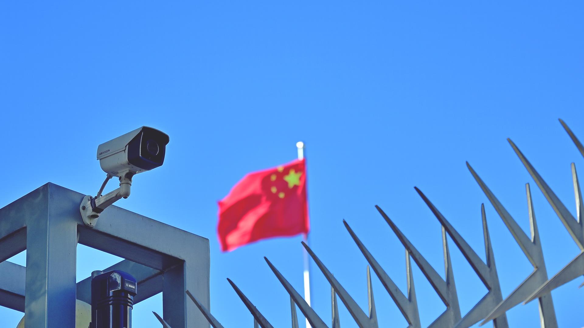 Symbolbild "China" Kamera am Zaun des Chinesischen Generalkonsulats in Frankfurt am Main, im Hintergrund weht die Flagge der Volksrepublik China.