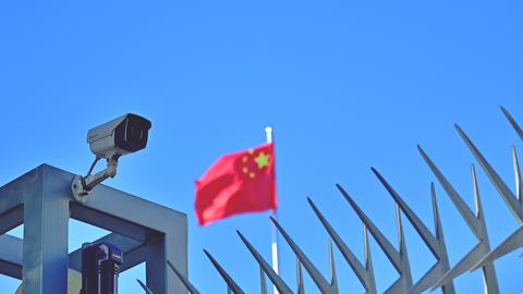 Symbolbild "China" Kamera am Zaun des Chinesischen Generalkonsulats in Frankfurt am Main, im Hintergrund weht die Flagge der Volksrepublik China.