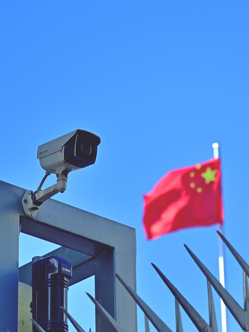 Symbolbild "China" Kamera am Zaun des Chinesischen Generalkonsulats in Frankfurt am Main, im Hintergrund weht die Flagge der Volksrepublik China.