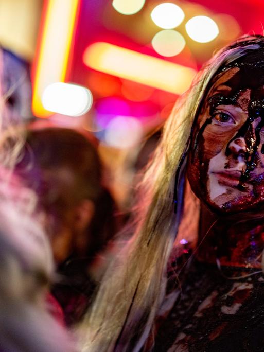 Eine Frau mit viel Kunstblut im Gesicht nimmt zu Halloween in Essen an einem Zombiewalk teil.