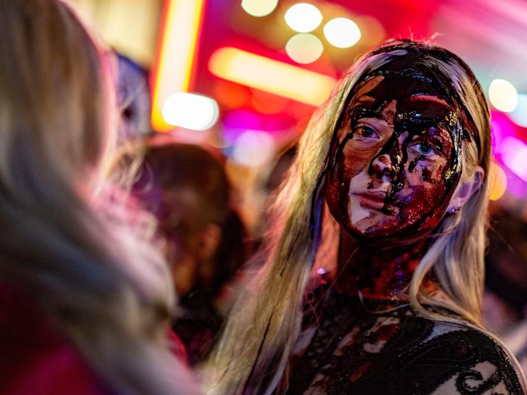 Eine Frau mit viel Kunstblut im Gesicht nimmt zu Halloween in Essen an einem Zombiewalk teil.