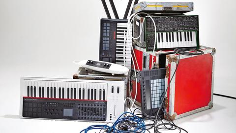 Eine Auswahl an Audio- und Musikequipment, darunter Synthesizer, Keyboards und Kabel.