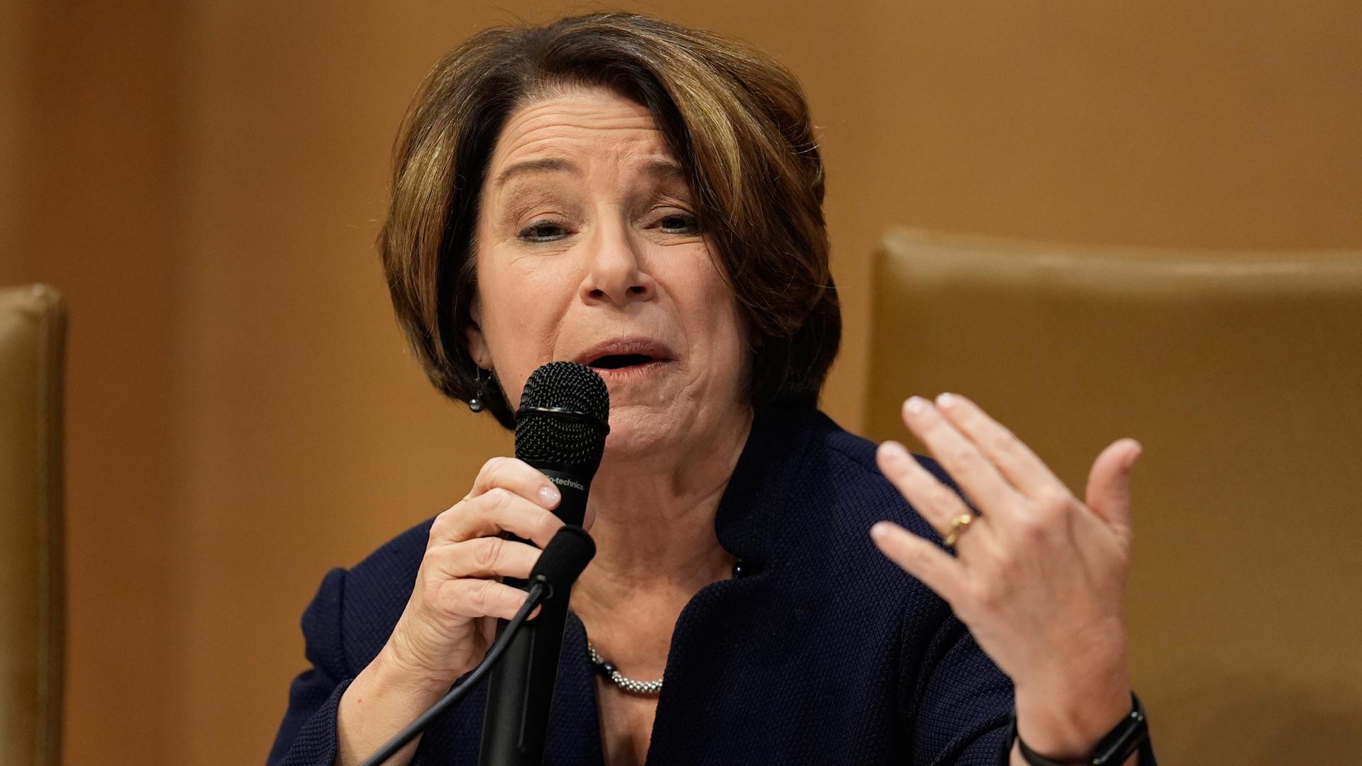 Die US-Senatorin Klobuchar spricht in ein Mikrofon und gestikuliert mit der linken Hand.