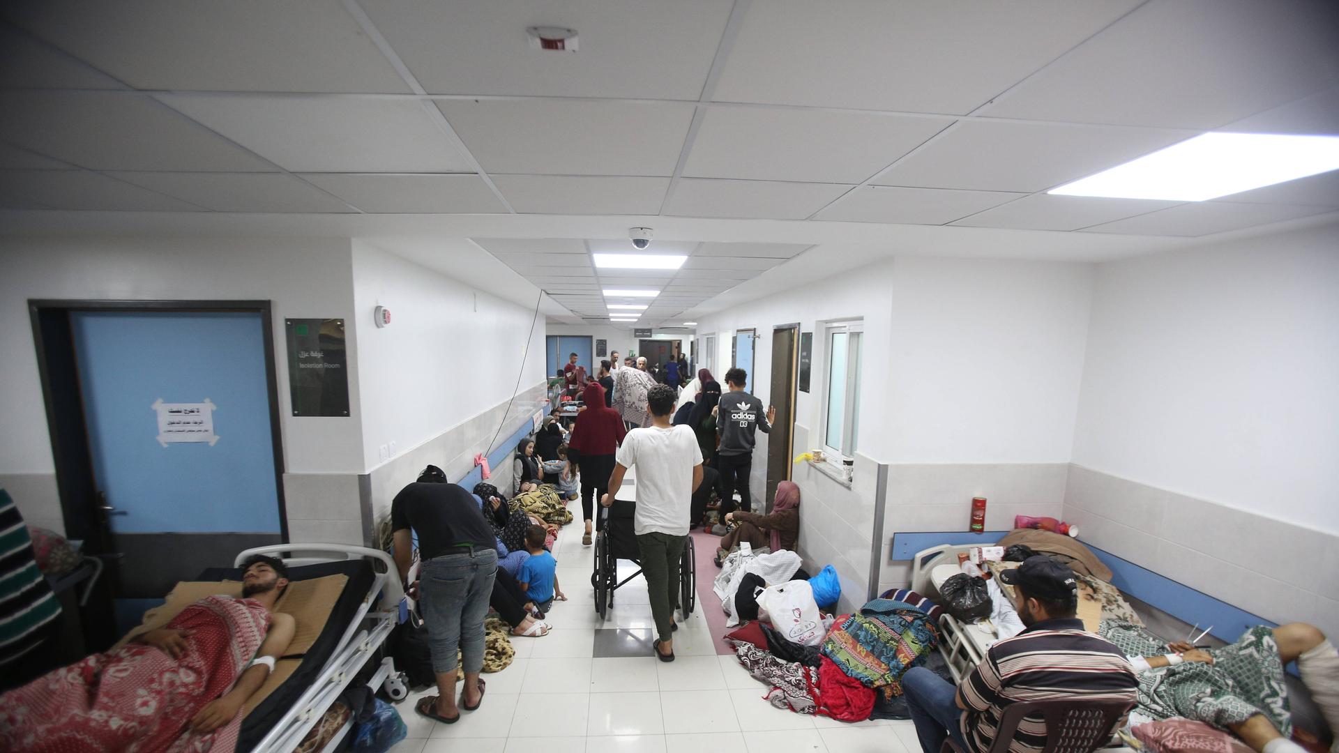 Das Bild zeigt einen Flur des Al-Schifa-Krankenhauses in Gaza, zahlreiche Menschen liegen, sitzen und stehen auf dem Gang.