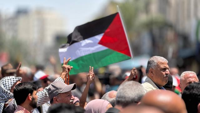 Menschen mit einer Palästinenserflagge demonstrieren im Westjordanland