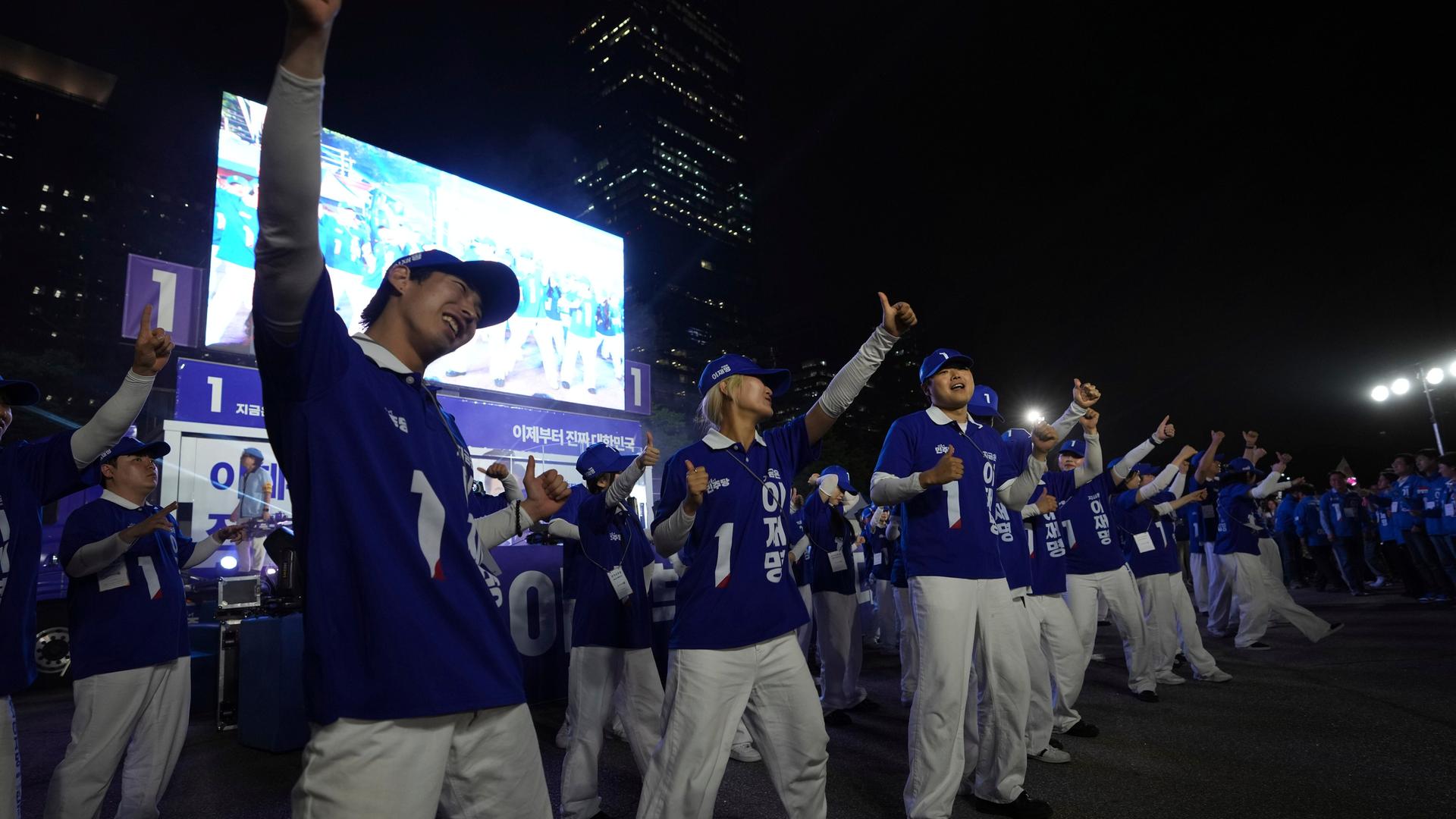 Anhänger des Präsidentschaftskandidaten der Demokratischen Partei Südkoreas, Lee Jae-myung, jubeln während einer Wahlkampagne in Seoul, Südkorea. Sie tragen violett-weiße Kleidung, die an amerikanische College- und Unviersitätskleidung erinnert.