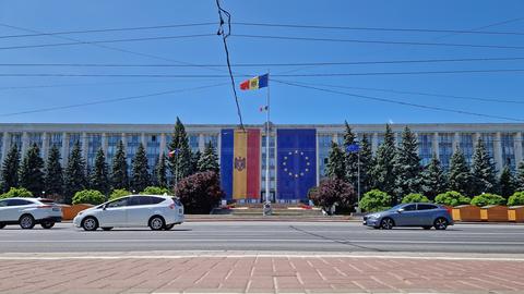 Am Regierungsgebäude in Chișinău hängen sowohl die moldauische Flagge als auch die Flagge der EU. Im Vordergrund verläuft eine Straße, in der Luft hängen Stromleitungen. Am Regierungsgebäude in Chișinău hängen sowohl die moldauische Flagge als auch die Flagge der EU. Im Vordergrund verläuft eine Straße, in der Luft hängen Stromleitungen.