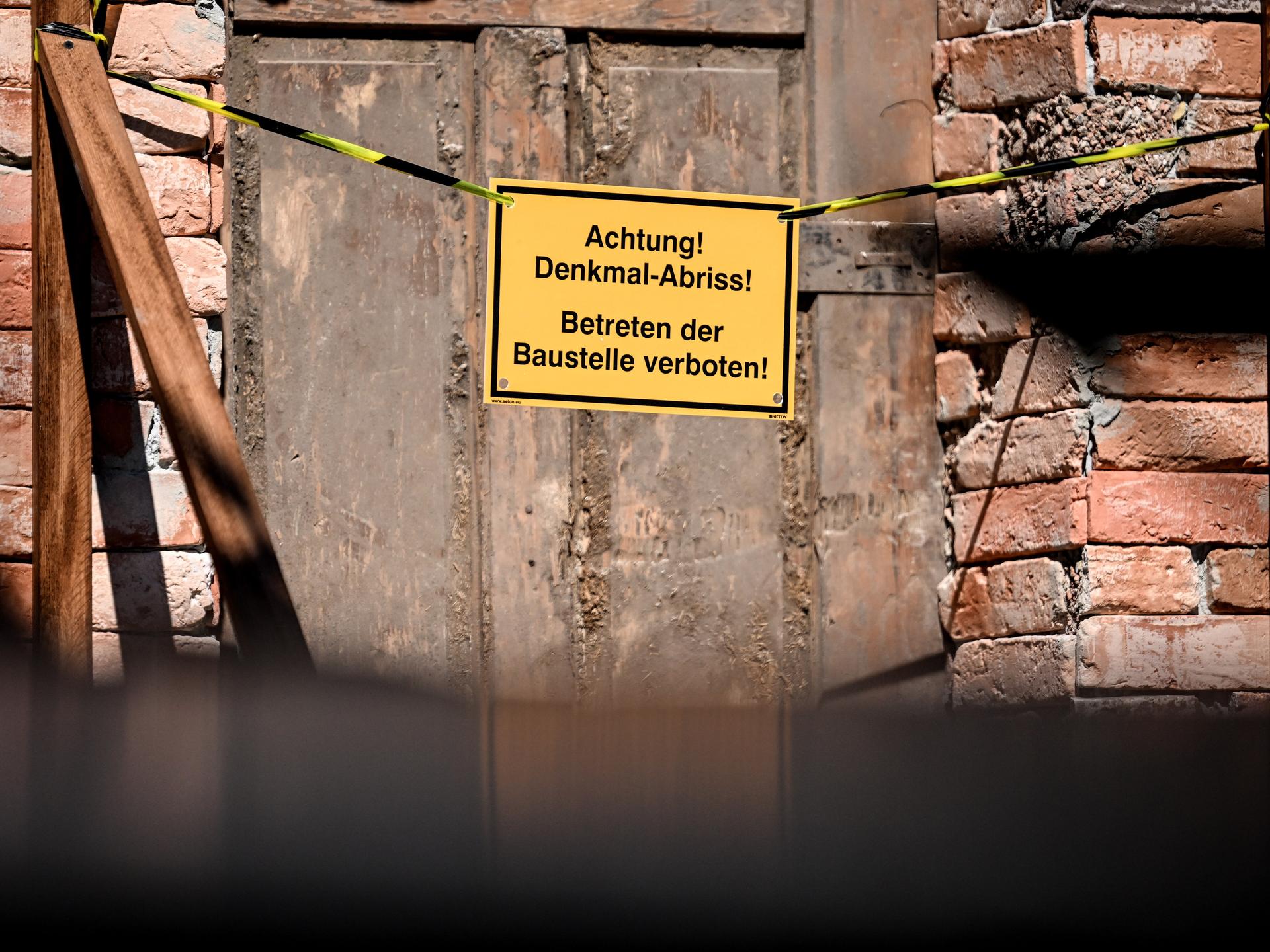 Auf einem Schild an der Tür einer baufälligen Fassade sind die Worte "Achtung! Denkmal Abriss! Betreten der Baustelle verboten!" zu lesen. Auf einem Schild an der Tür einer baufälligen Fassade sind die Worte "Achtung! Denkmal Abriss! Betreten der Baustelle verboten!" zu lesen.
