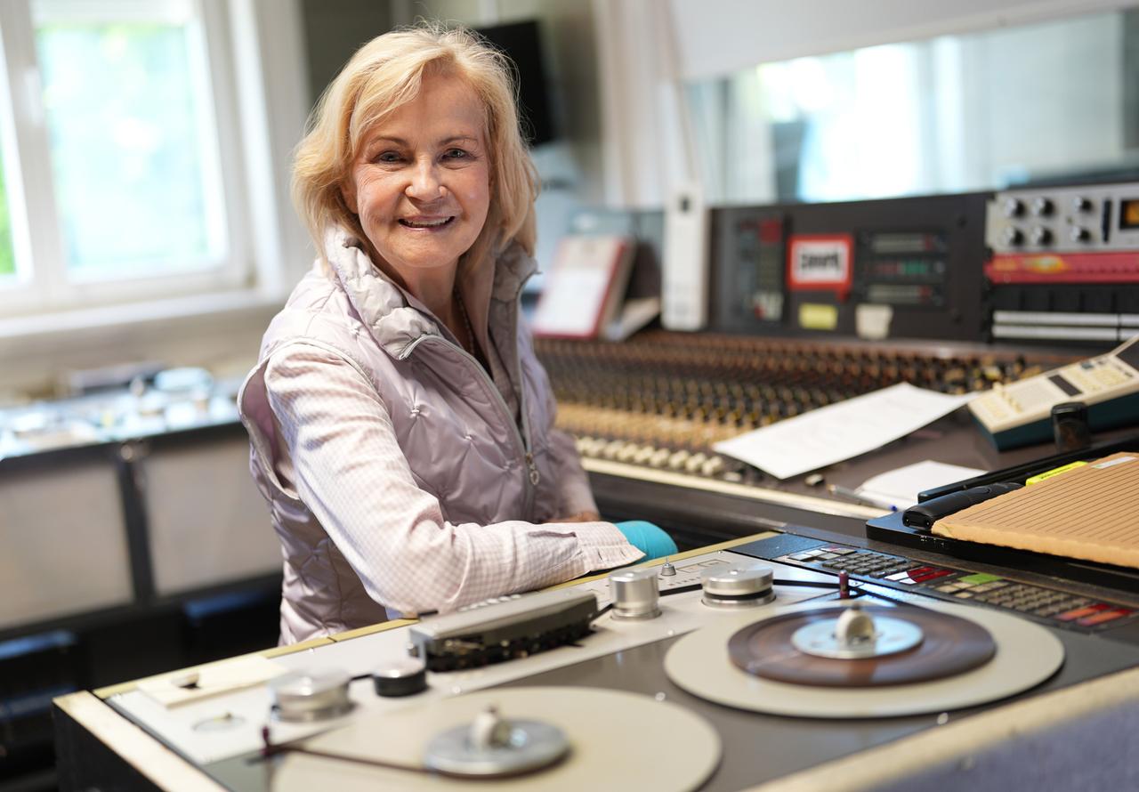 Eine Frau sitzt lächelnd hinter einer Bandmanschine. Eine Frau sitzt lächelnd hinter einer Bandmanschine.