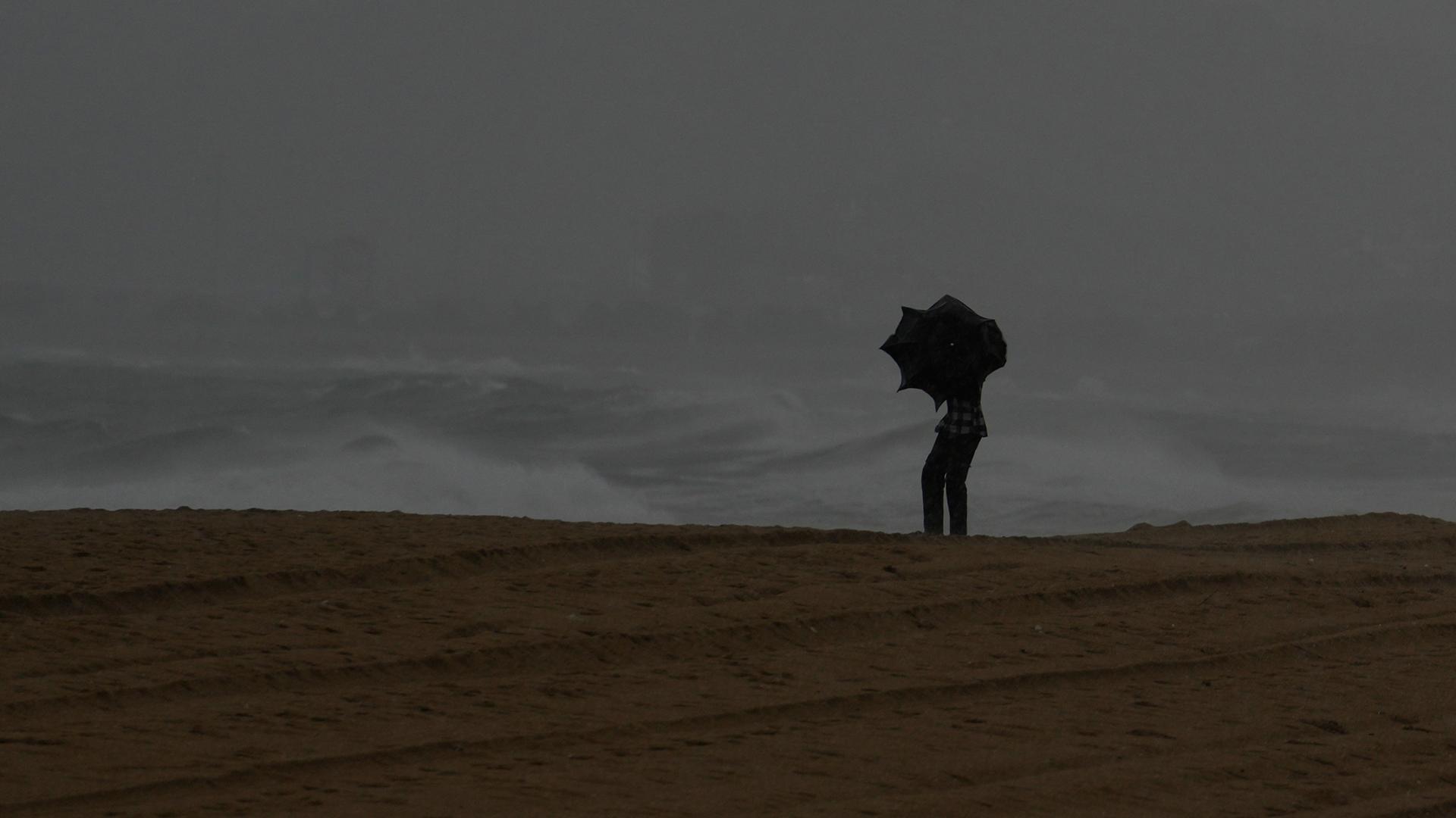 Visakhapatnam: Ein Besucher hält einen Regenschirm, als es am Ramakrishna-Strand an der Küste des Golfs von Bengalen während eines plötzlichen Sturms regnet. 