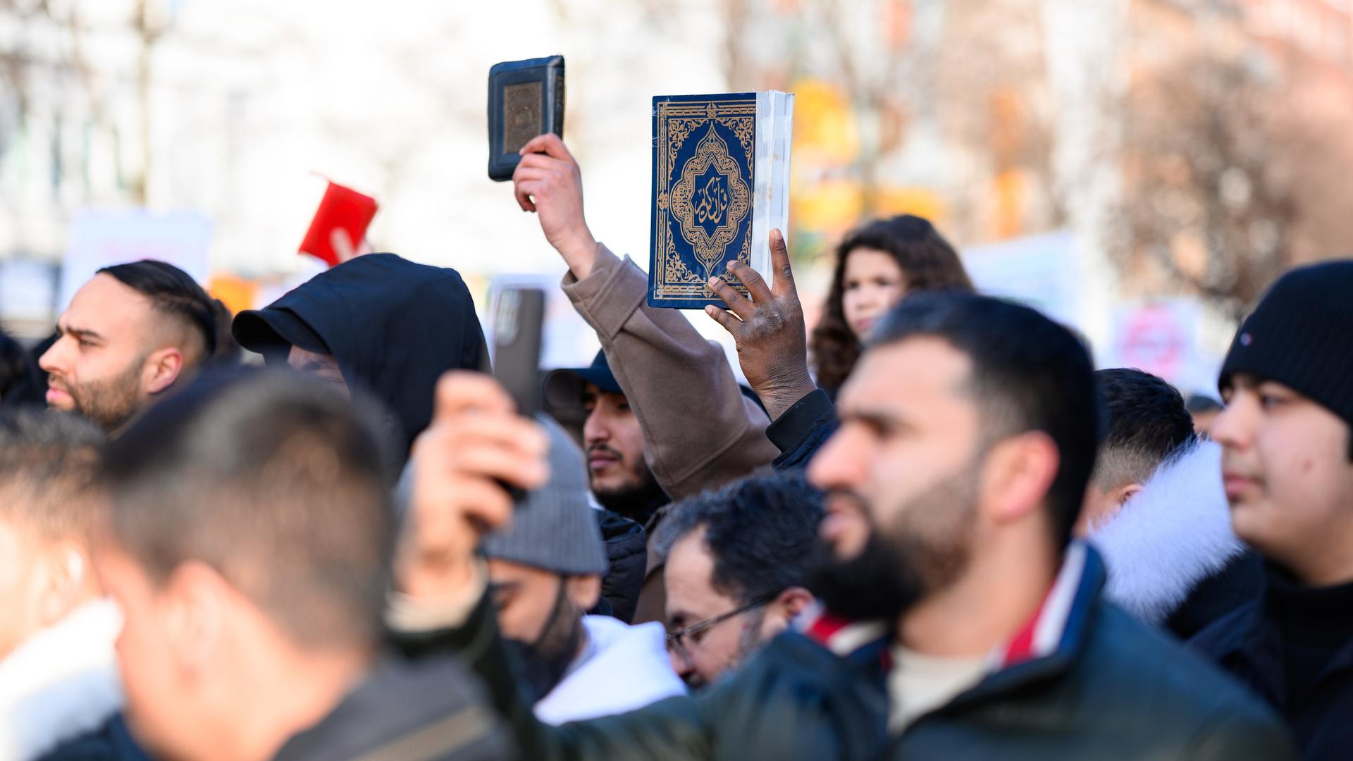 Teilnehmer einer Demo in Hamburg 2023 halten den Koran in die Höhe. 