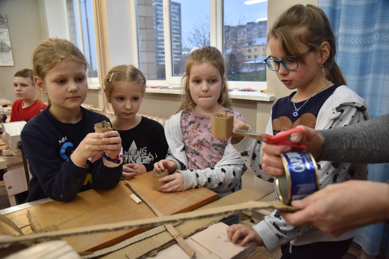 Vier Kinder stehen um einen Schultisch und basteln.