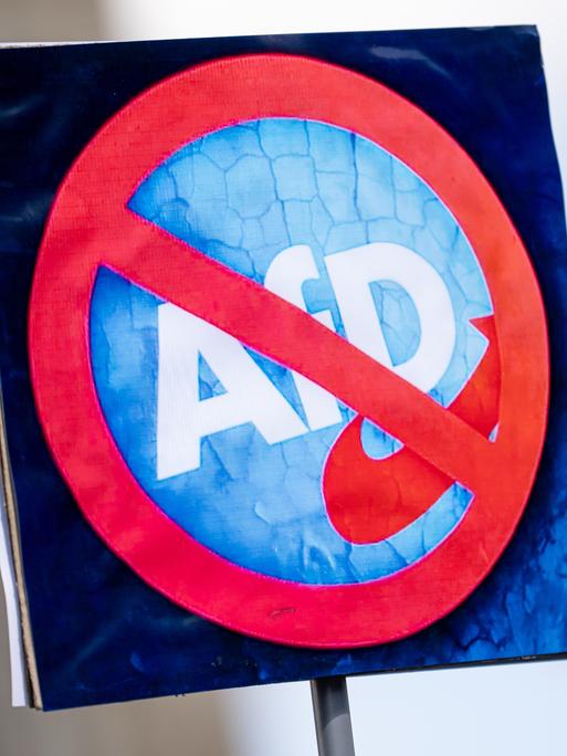 Eine Person hält am bundesweiten Aktionstag "Keine Ausreden mehr - AfD-Verbot jetzt!" am 11. Mai 2025 ein Schild mit einem durchgestrichenen Logo der AfD. 