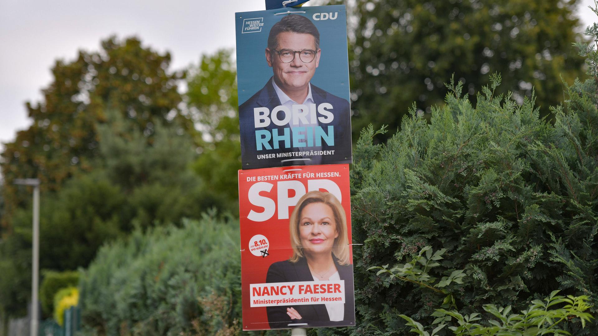 Wahlplakate für die Landtagswahl in Hessen: Das obere Plakat zeigt den CDU-Spitzenkandidaten Boris Rhein, darunter hängt Wahlwerbung der SPD mit Spitzenkandidatin Nancy Faeser.
