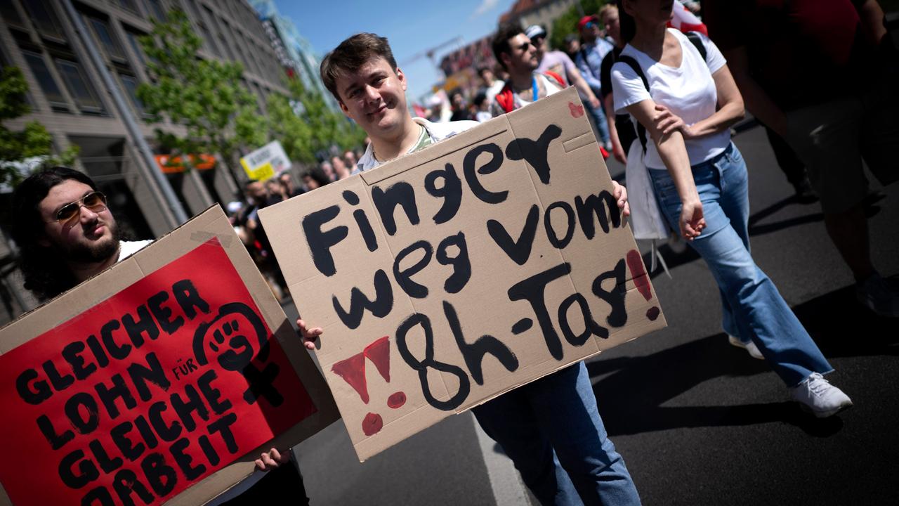 Demonstranten halten Plakate hoch: "Finger weg vom 8-Stunden-Tag" und "Gleicehr Lohn für gleiche Arbeit". Demonstranten halten Plakate hoch: "Finger weg vom 8-Stunden-Tag" und "Gleicehr Lohn für gleiche Arbeit".