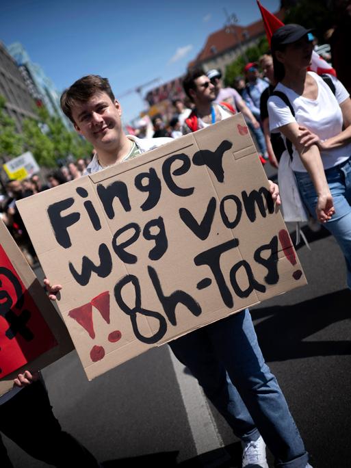 Demonstranten halten Plakate hoch: "Finger weg vom 8-Stunden-Tag" und "Gleicehr Lohn für gleiche Arbeit". Demonstranten halten Plakate hoch: "Finger weg vom 8-Stunden-Tag" und "Gleicehr Lohn für gleiche Arbeit".