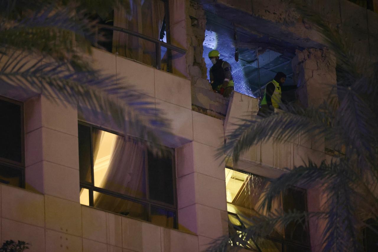 Personen in gelber Schutzausrüstung sind durch die zerstörte Fassade des Ramada Hotels in Beirut zu sehen. 