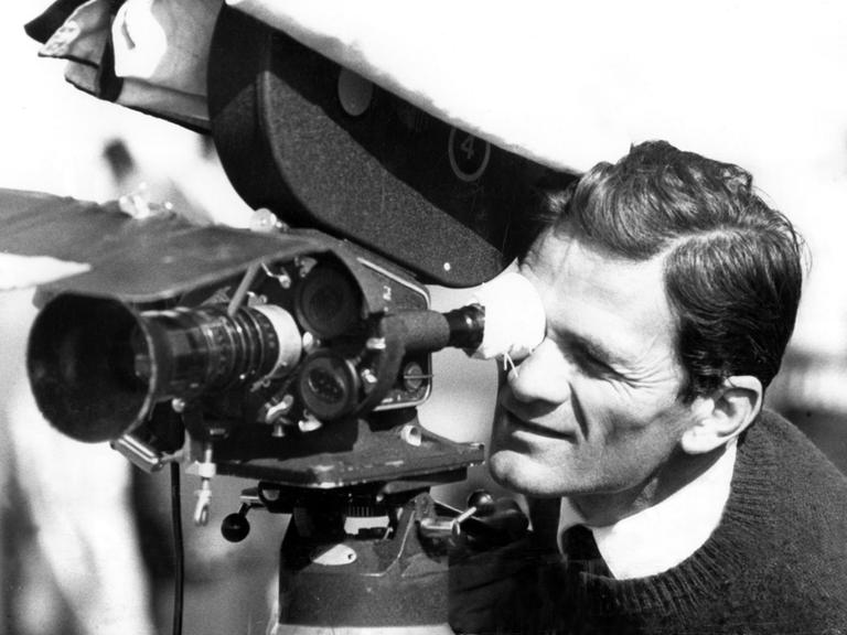 Pier Paolo Pasolini an einem Filmset im Jahr 1962. Er schaut durch eine Kamera.