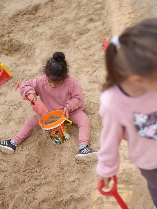 Zwei Kinder spielen draußen in einem Sandkasten in Berlin. (Symbolbild)