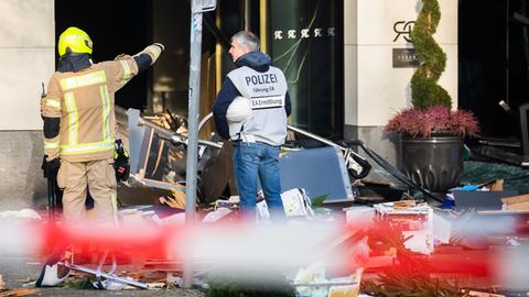 Ein Polizeibeamter begutachtet neben einem Feuerwehrmann auf der Karl-Liebknecht-Straße Trümmer vor einem Hotel.