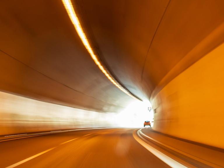 Ein Auto fährt durch einen Straßentunnel - am Ende ist das Licht sichtbar