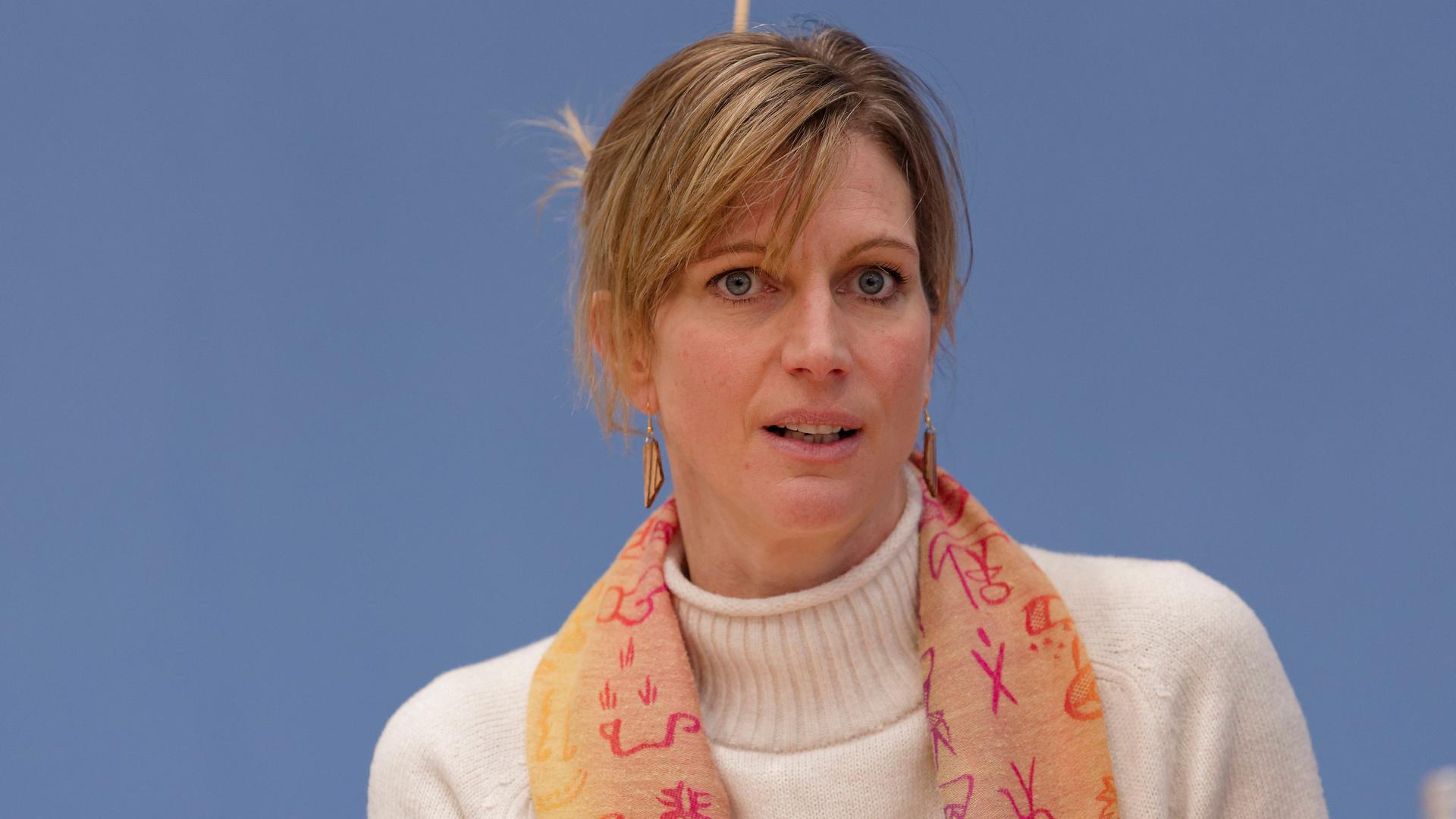 Die Transformationsforscherin Maja Göpel guckt leicht skeptisch. Sie trägt einen orangen Schal und einen weißen Wollpulli.