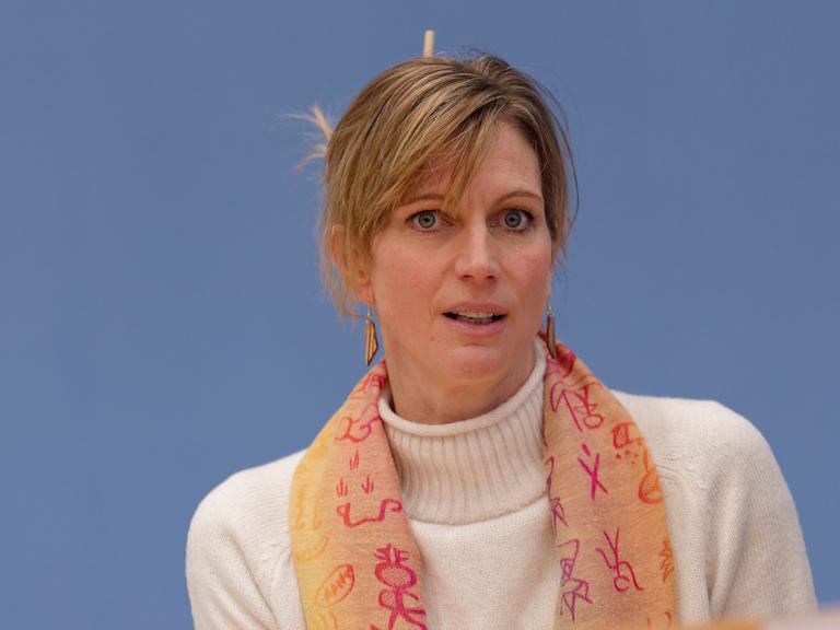Die Transformationsforscherin Maja Göpel guckt leicht skeptisch. Sie trägt einen orangen Schal und einen weißen Wollpulli.